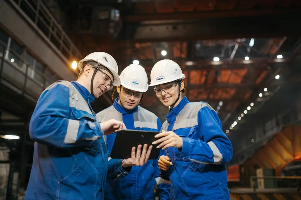 Engineers in hard hats reviewing work on a tablet on site